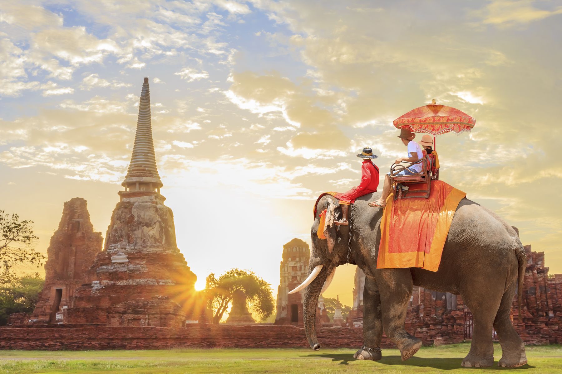 Turistas en un paseo por elefante en la ciudad antigua con el amanecer de fondo, Camboya